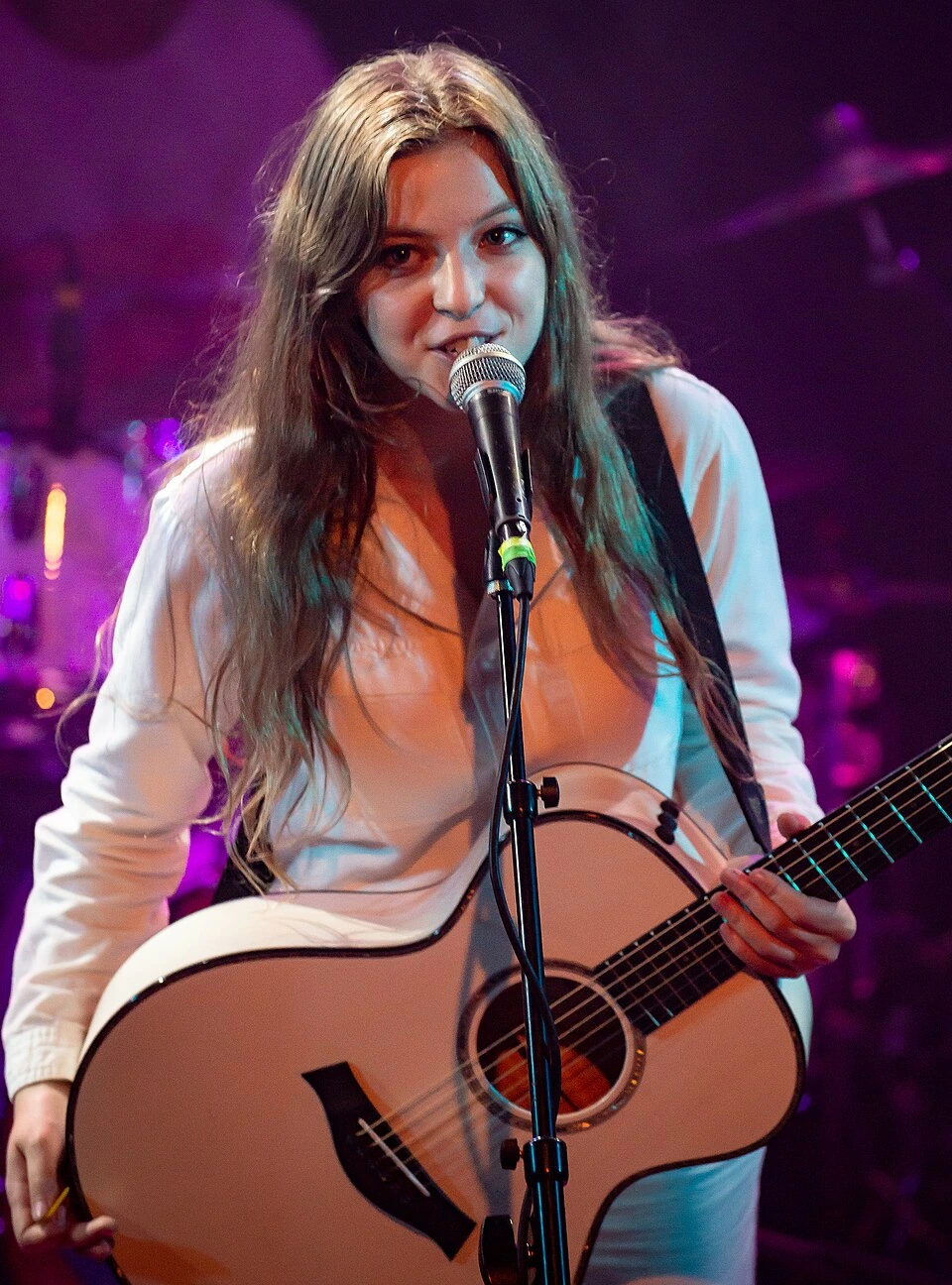 Birdy performing on stage with a guitar and microphone